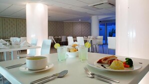 A dining area with tables set for meals, including plates of food and drinks. - Adhara Express (Cancun)