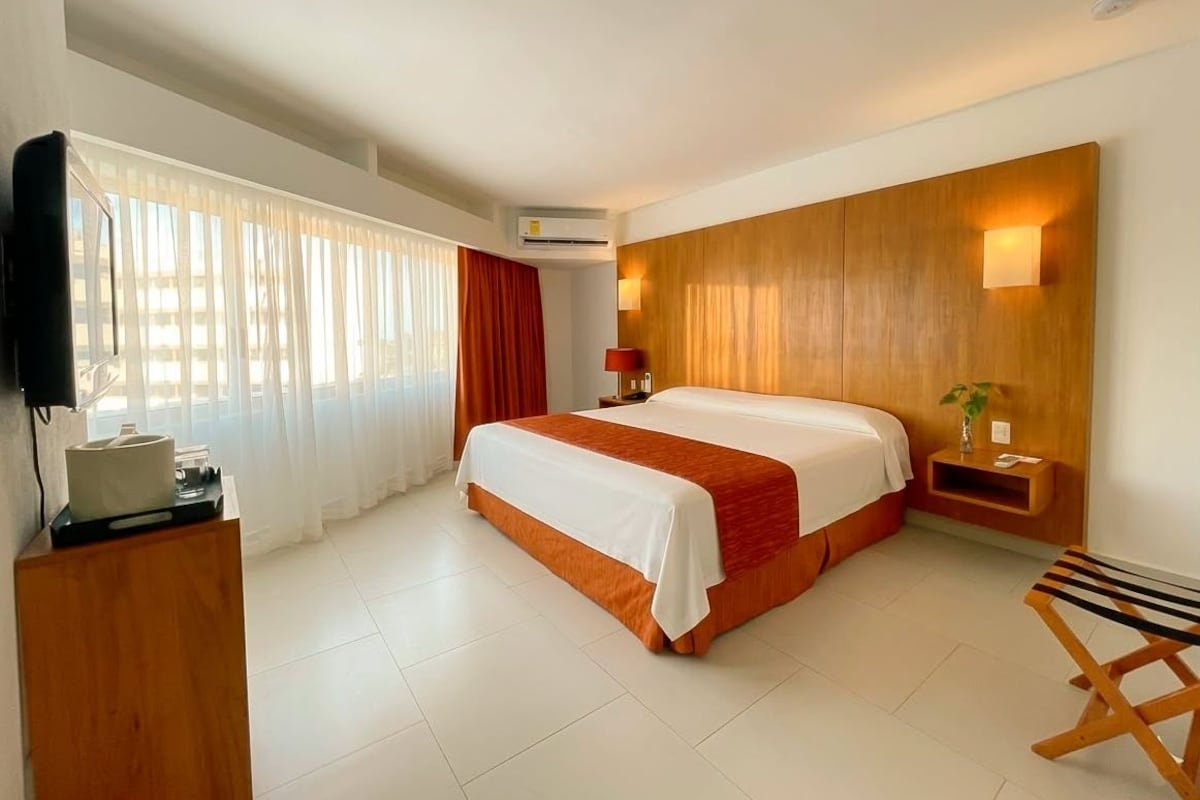 Une chambre d’hôtel avec un grand lit, un bureau, une chaise et un téléviseur.