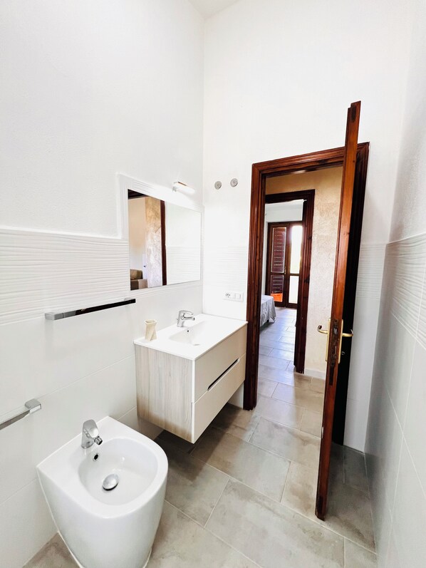Une salle de bain moderne avec un lavabo blanc, un miroir et un meuble-lavabo.