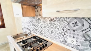 A modern kitchen with a gas stove, wooden cabinets, and patterned backsplash tiles. - Residence La Cinta 7 1P (San Teodoro)