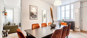 Un comedor moderno con una mesa de madera oscura, sillas tapizadas en color naranja y un florero con plumas de pampa.