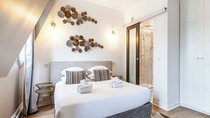 A modern bedroom with a large bed, two bedside tables, a wall art piece, and a sliding door closet.