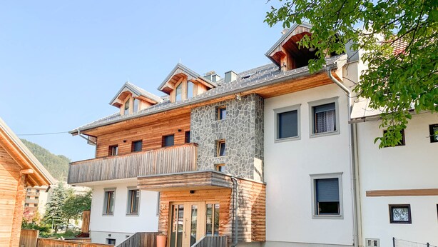 A multi-story building with a stone facade, wooden balconies, and a staircase leading to the entrance. - Old Village House - Holiday Nest (Bohinjska Bistrica)
