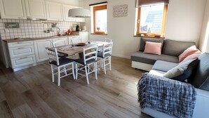 A compact kitchen with white cabinets, a dining table with chairs, and a sofa with a blanket. - Old Village House - Holiday Nest (Bohinjska Bistrica)
