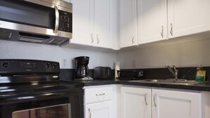 A kitchen with white cabinets, a black stove, a microwave, and a coffee maker. - Miami Beach 1BR · 2 Blocks to Sand on Collins Ave (Miami Beach)