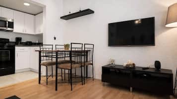 A modern kitchen with white cabinets, a black countertop, and a dining area with a table and chairs.