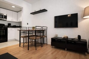 Una cocina moderna con armarios blancos, una encimera negra y un comedor con mesa y sillas.