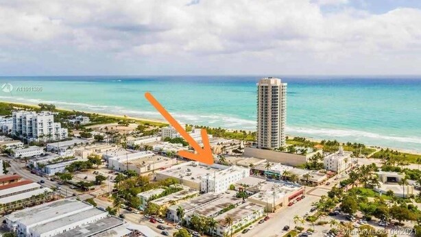 An aerial view of a coastal city with a prominent high-rise building, a beach, and a mix of residential and commercial buildings. - Miami Beach 1BR · 2 Blocks to Sand on Collins Ave (Miami Beach)