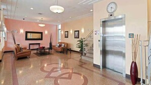 A hotel lobby with a reception desk, seating area, elevator, and a clock on the wall. - Miami Beach 1BR · 2 Blocks to Sand on Collins Ave (Miami Beach)