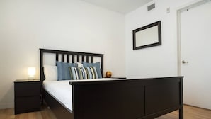 A bedroom with a dark wooden bed, white bedding, and a nightstand with a lamp. - Miami Beach 1BR · 2 Blocks to Sand on Collins Ave (Miami Beach)