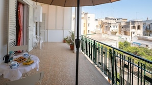 Ein Balkon mit Frühstückstisch, einem Blumentopf und Blick auf die umliegenden Gebäude.