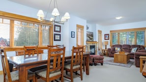 A dining area with a wooden table and chairs, a fireplace, and a living room with a sofa and a coffee table.