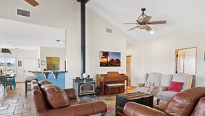 A spacious living room with leather sofas, a piano, a fireplace, and a dining area with a view. - Dark Horse Ranch · Single-Story Home on 5 Acres · Sleeps 8 · Dog-Friendly (Yucca Valley)