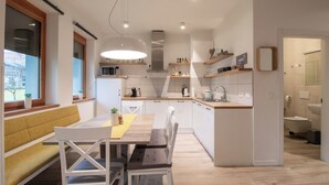 A modern kitchen with a central island, built-in appliances, and a dining area with a bench and table. - Old Village House - Catherine's place (Bohinjska Bistrica)