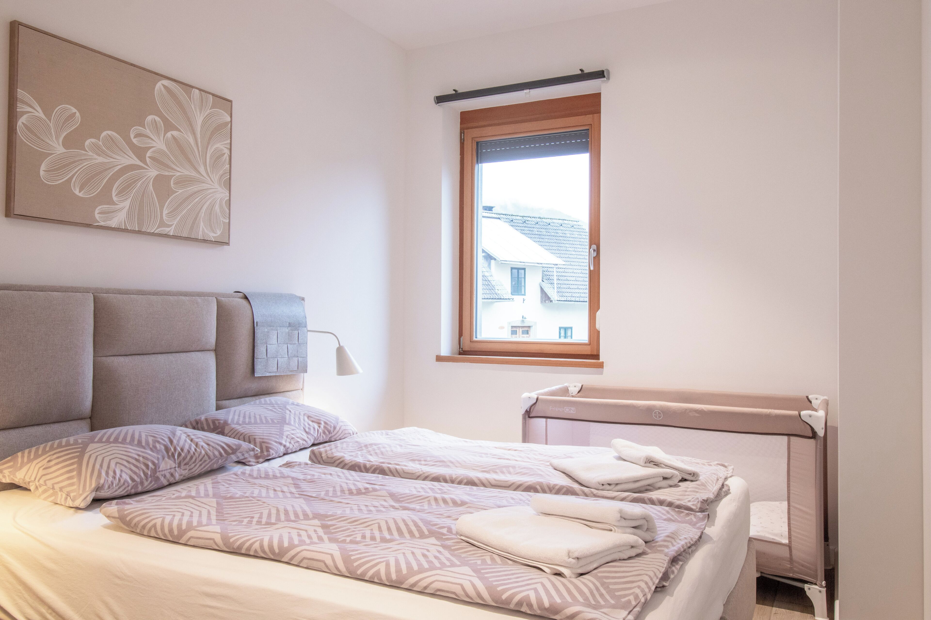 A bedroom with a bed, a headboard, a window, and a radiator.