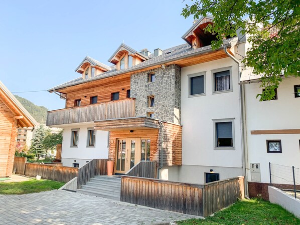 A multi-story building with a stone facade, wooden balconies, and a staircase leading to the entrance.