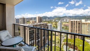 Un balcón con vistas a un paisaje urbano, incluyendo edificios altos y montañas a lo lejos.
