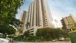 Un edificio de gran altura con varios pisos, rodeado de follaje y palmeras.