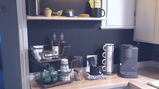 Een keuken met een neonbord met de tekst 'coffee', een koffiezetapparaat en diverse keukengerei en apparaten.