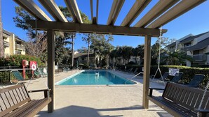 A pool area with a wooden pergola, lounge chairs, and a sign indicating no lifeguard on duty. - Spacious, cozy villa in Coligny Villas (Hilton Head Island)