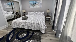 A modern hotel room with a large bed, two bedside tables, and a mirror. - Spacious, cozy villa in Coligny Villas (Hilton Head Island)