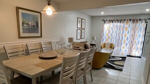 A dining area with a wooden table and chairs, a hanging light fixture, and a framed picture on the wall. - Spacious, cozy villa in Coligny Villas (Hilton Head Island)