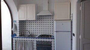 A compact kitchen with white cabinets, a gas stove, and a refrigerator.