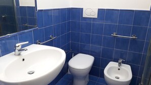 A bathroom with a white sink, a toilet, and a bidet.