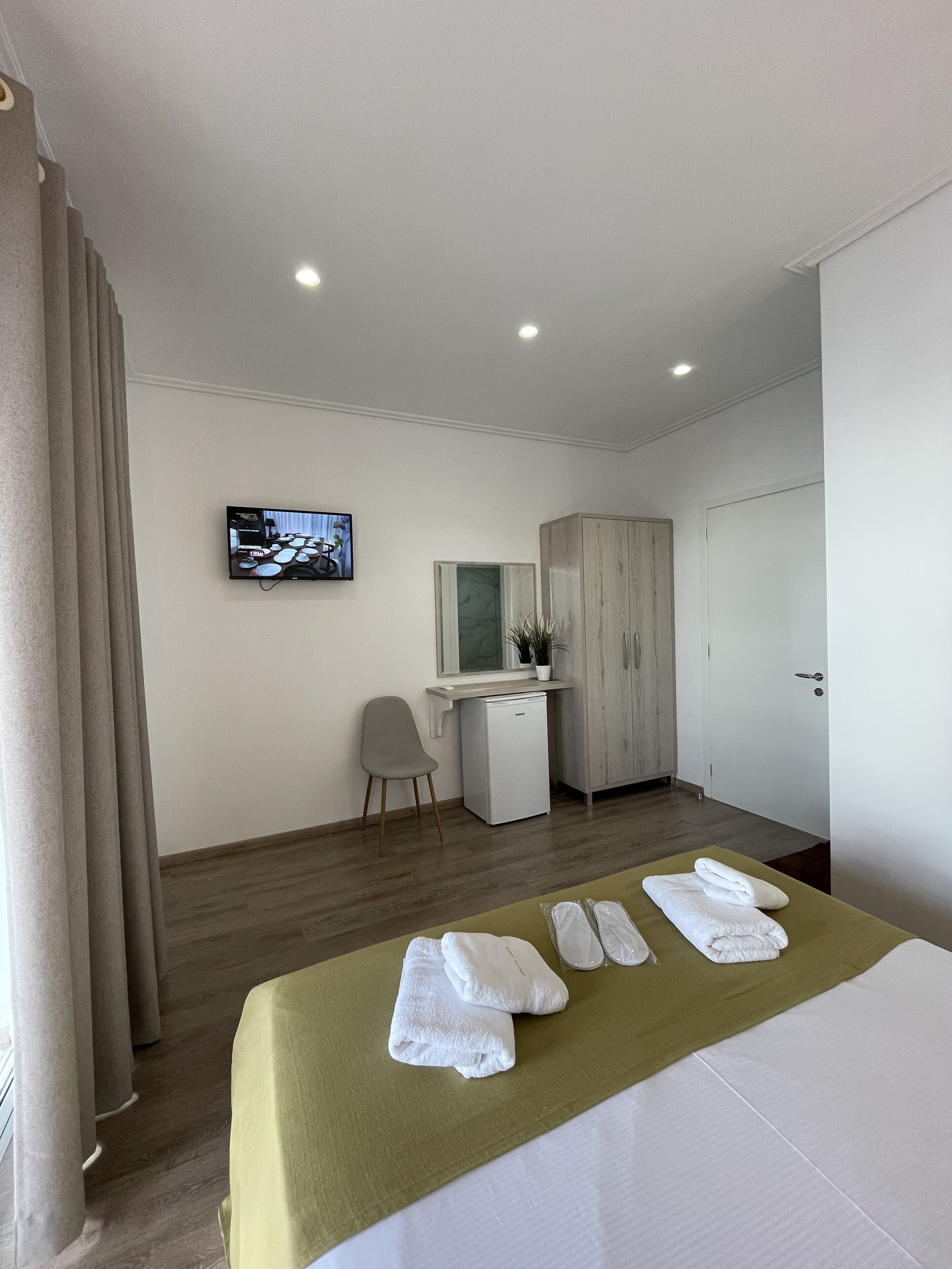 Une chambre d’hôtel équipée d’un lit, d’un bureau, d’une chaise, d’une armoire et d’un téléviseur fixé au mur.