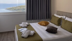 A hotel room with a bed, a window with a view of the sea, and an air conditioning unit on the wall. - Relax Mea Hotel (Sarandë)