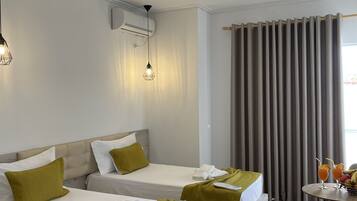 A hotel room with two beds, a small table with fruit, and a window with curtains.