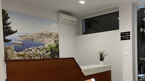 A reception desk with a marble floor, a cityscape mural, and a modern air conditioning unit. - Relax Mea Hotel (Sarandë)