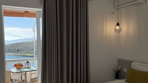 Habitació d'hotel amb un llit, una taula amb fruita, vista al mar i un balcó.