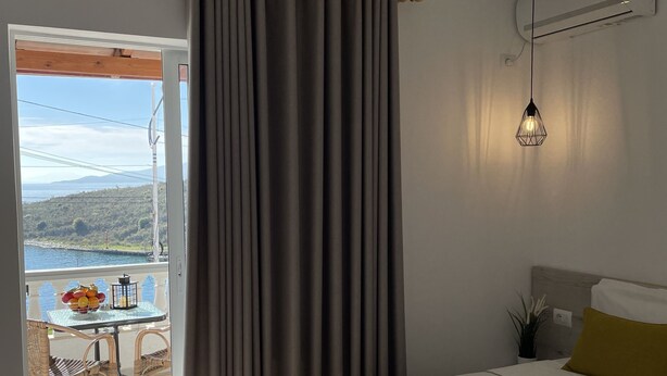 A hotel room with a bed, a table with fruit, a view of the sea, and a balcony. - Relax Mea Hotel (Sarandë)