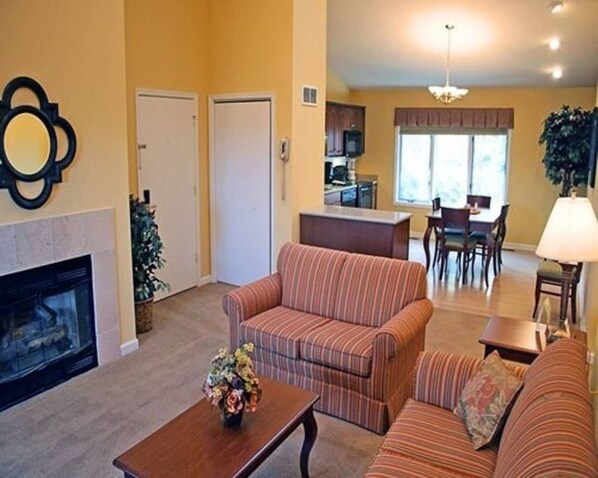 A living room with striped sofas, a fireplace, and a dining area with a table and chairs.