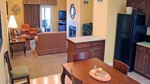 Un espacio habitable compacto con comedor, kitchenette y zona de estar con televisor.