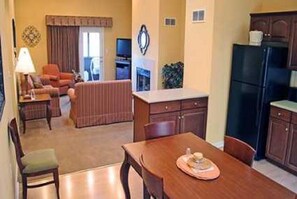 A compact living space with a dining area, kitchenette, and a seating area with a television.