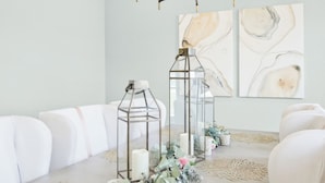 A dining area with a table set for four, featuring a chandelier, wall art, and decorative elements. - Watch Cargo Ships Glide by from This Walkable Savannah River Retreat (Savannah)