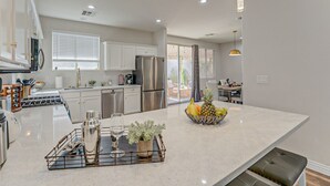 Uma cozinha moderna com uma ilha central, eletrodomésticos de aço inoxidável e iluminação pendente.