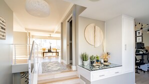 A modern kitchen with a marble countertop, wooden flooring, and a large round wall decoration. - Ocean View Designer Retreat w/ EV Charger (San Diego)