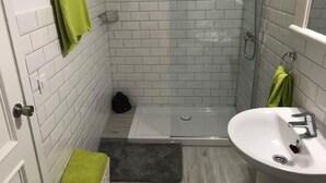 A small, tiled bathroom with a shower, a sink, and a toilet. - MAXORATA TOWN FUERTEVENTURA (Morro Jable)