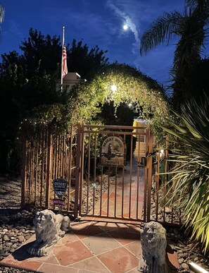 A gated entrance to a private desert house with a stone lion statue at the base. - Apt H- upstairs furnished 2bed/2bath in DT Palm Springs with mountain view  (Palm Springs)