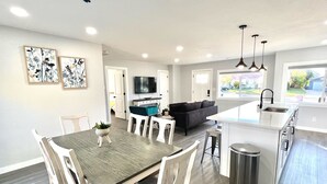 A modern kitchen with a central island, white cabinetry, and a large window providing a view of the outside.