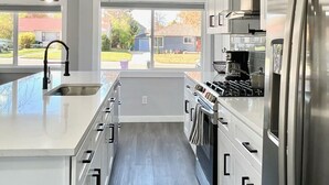 A modern kitchen with a central island, stainless steel appliances, and a view to the outdoors.