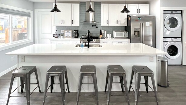 A modern kitchen with a large island, stainless steel appliances, and pendant lighting.