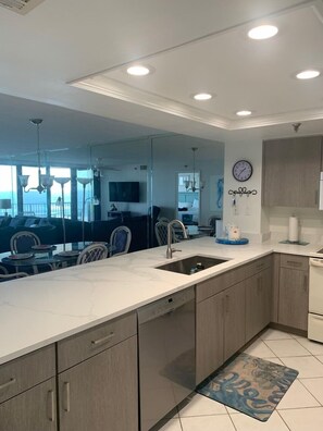 A modern kitchen with a large island, built-in appliances, and a view to the living area.