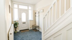 A hallway with a blue carpet, white walls, a white door with a window, and a staircase with white railings. - 4 Dorothy Avenue (Skegness)