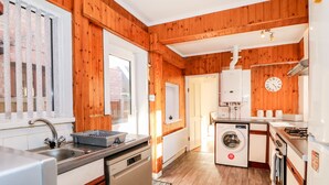 A kitchen with wooden walls, a washing machine, a dishwasher, and a sink. - 4 Dorothy Avenue (Skegness)