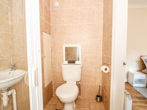 A bathroom with a toilet, sink, and shower area. - 4 Dorothy Avenue (Skegness)
