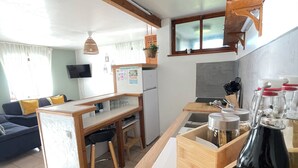 Een moderne keuken met houten aanrecht, een ingebouwde oven, en een eethoek met een houten tafel en stoelen.